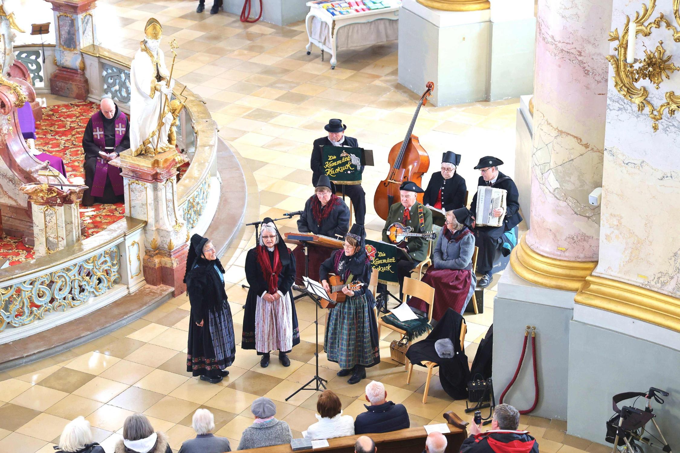 Die „Kemmärä Kuckuck“ (sitzend) umrahmten die fränkische Passion in der Basilika mit besinnlichen Tönen und Gesängen musikalisch. Davorstehend sind die „Kronicher Maala“, die ihre Lieder, wie die anderen Musikanten auch, allesamt im fränkischen Dialekt sangen.