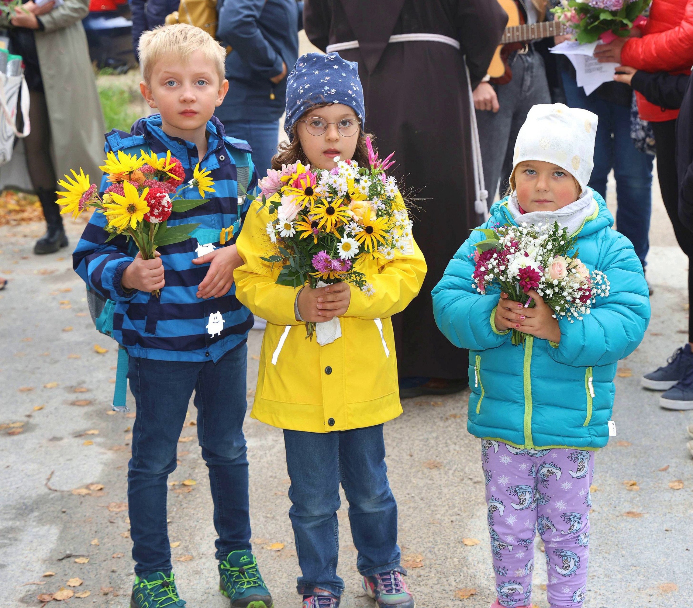 Die Vorschulkinder Fabian, Magdalena und Selina zeigen voller Stolz ihr kleines Blumensträußchen, das sie bei der Ankunft in Vierzehnheiligen erhielten.