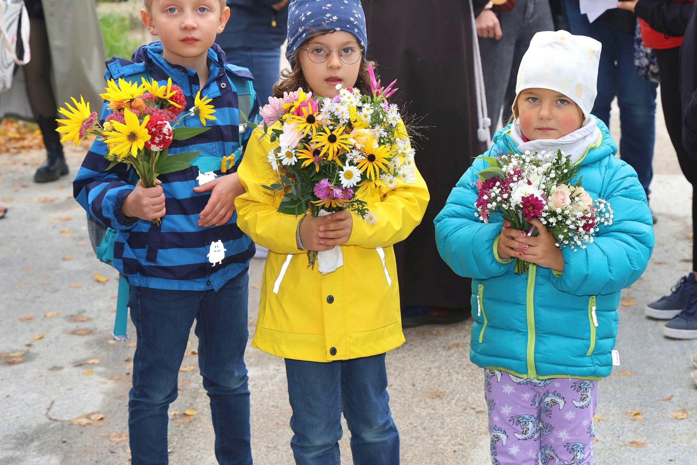Die Vorschulkinder Fabian, Magdalena und Selina zeigen voller Stolz ihr kleines Blumensträußchen, das sie bei der Ankunft in Vierzehnheiligen erhielten.